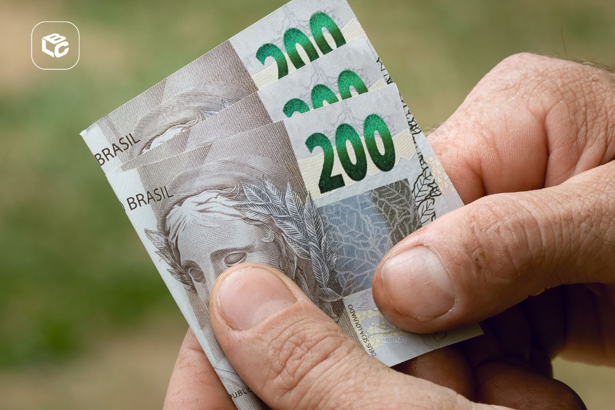 Pessoa segurando três notas de R$ 200 nas mãos, representando recebimento de dinheiro, pagamento de precatório, RPV ou antecipação de crédito.
